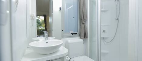 A modern bathroom with a white sink, toilet, and glass shower enclosure.