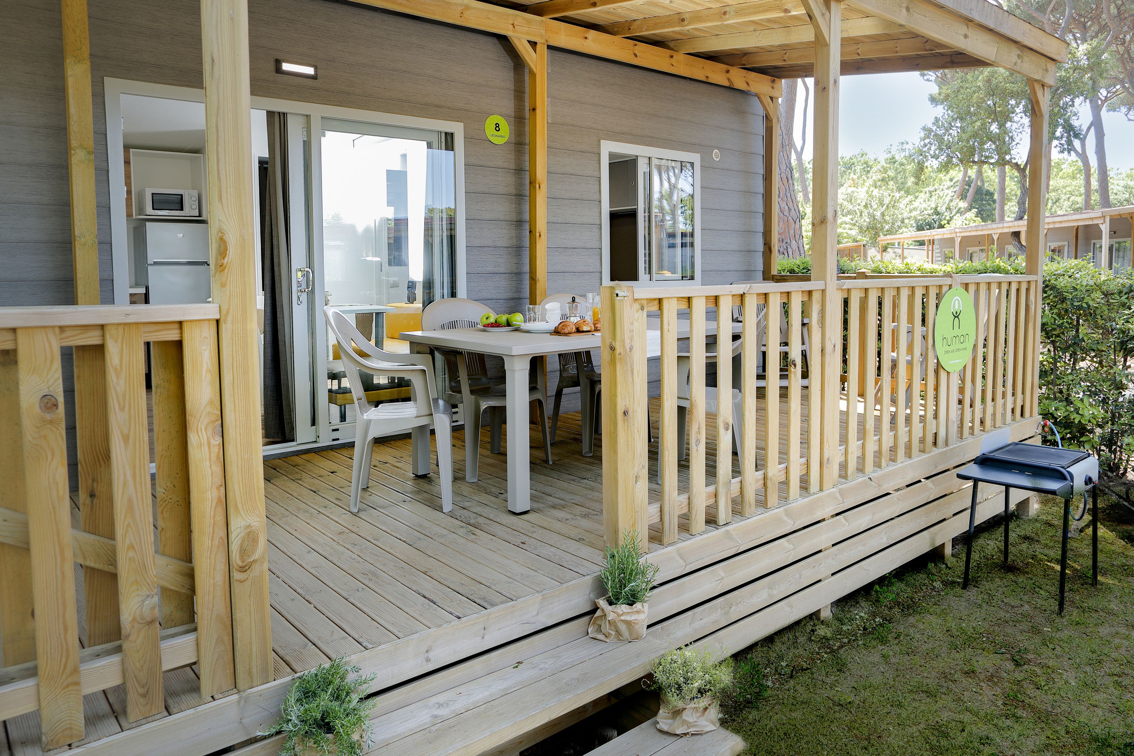 A wooden deck with a table and chairs, a grill, and a small garden area.