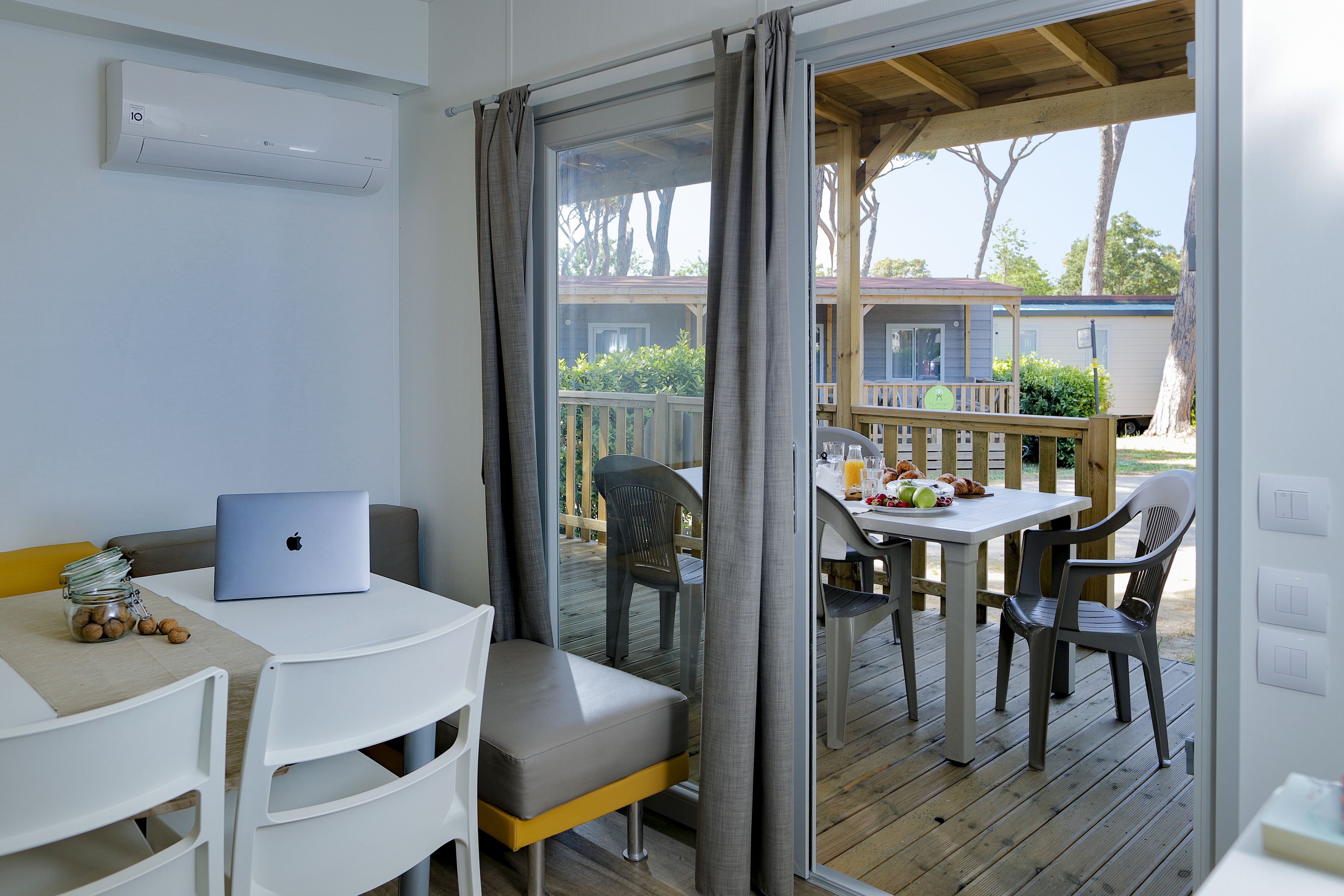 A room with a laptop on a table, a chair, and a window with curtains.