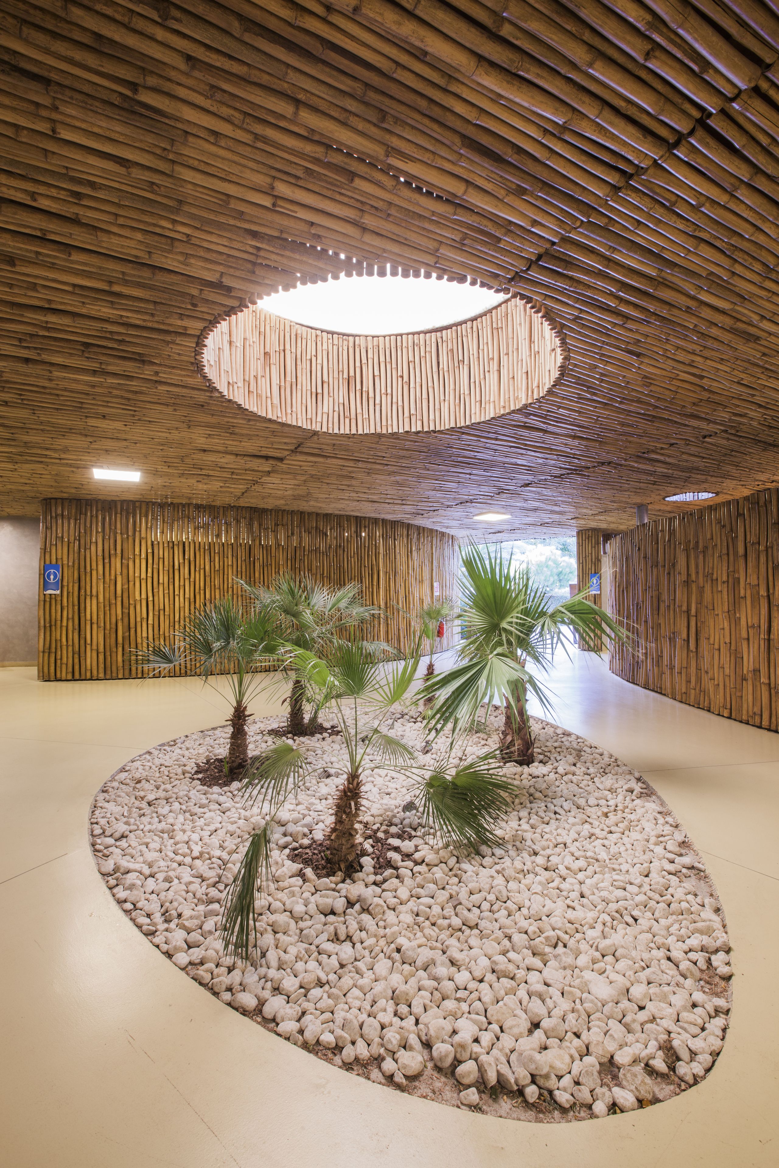 A lobby with a circular seating area, bamboo walls, and a central light fixture.