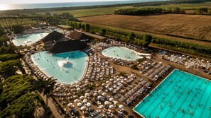 Vista aérea de un complejo turístico con varias piscinas, tumbonas y sombrillas.