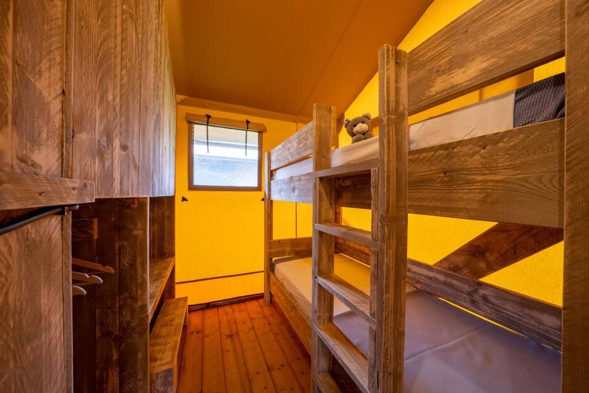 Habitación con literas, paredes de madera y una ventana.