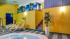 Un hall d’hôtel avec un espace piscine, des murs jaunes, un escalier et une fresque représentant des palmiers.