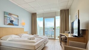 Une chambre d’hôtel avec un lit, un bureau et une chaise, une télévision et un balcon avec vue.