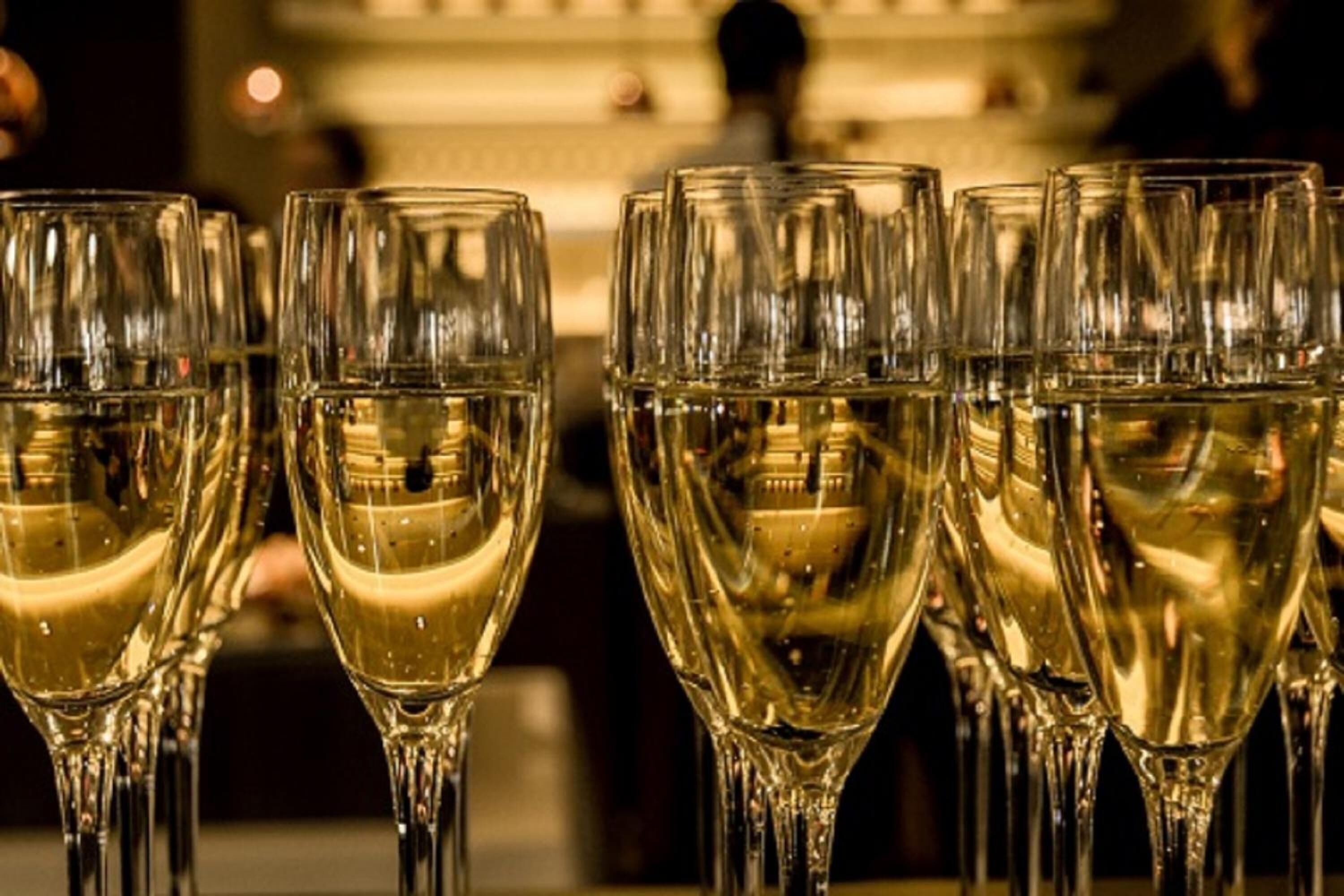 A row of empty champagne flutes on a bar counter.