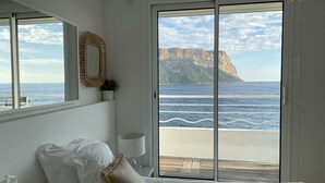 Une chambre avec une grande fenêtre donnant sur la mer et les falaises.
