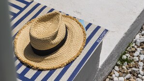 Een stroohoed op een stenen bank met een blauw-witte streepdoek.