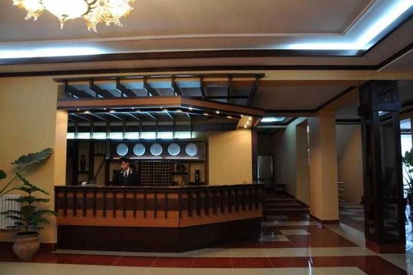 A reception area with a counter, a staircase, and a potted plant.