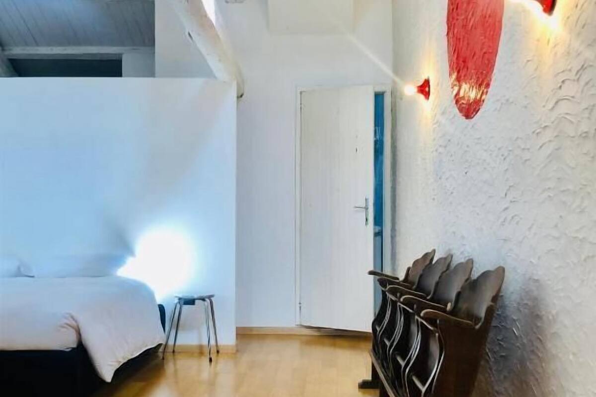 Ein Zimmer mit einem Bett, einem kleinen Tisch und einer Wandleuchte.
