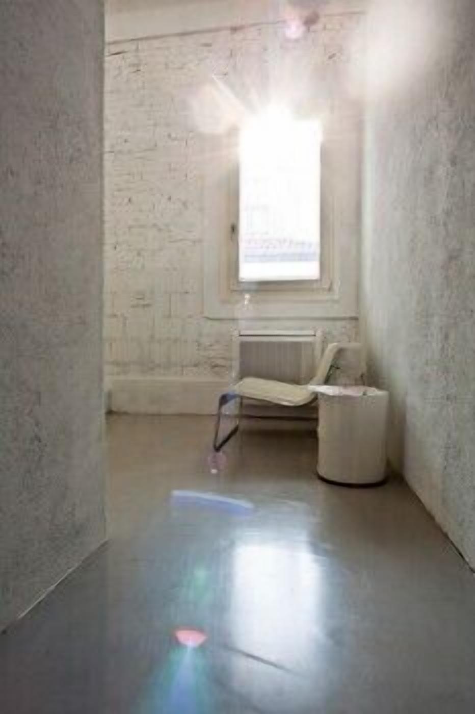A room with a concrete floor, a window with a view, and a radiator.
