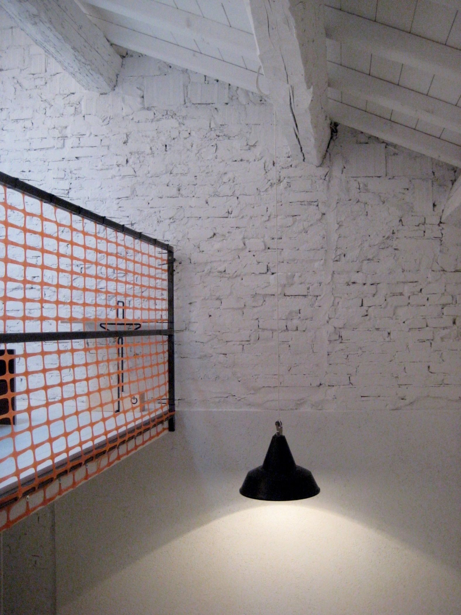 A room with white brick walls, a black object on the floor, and an orange safety net on the left.
