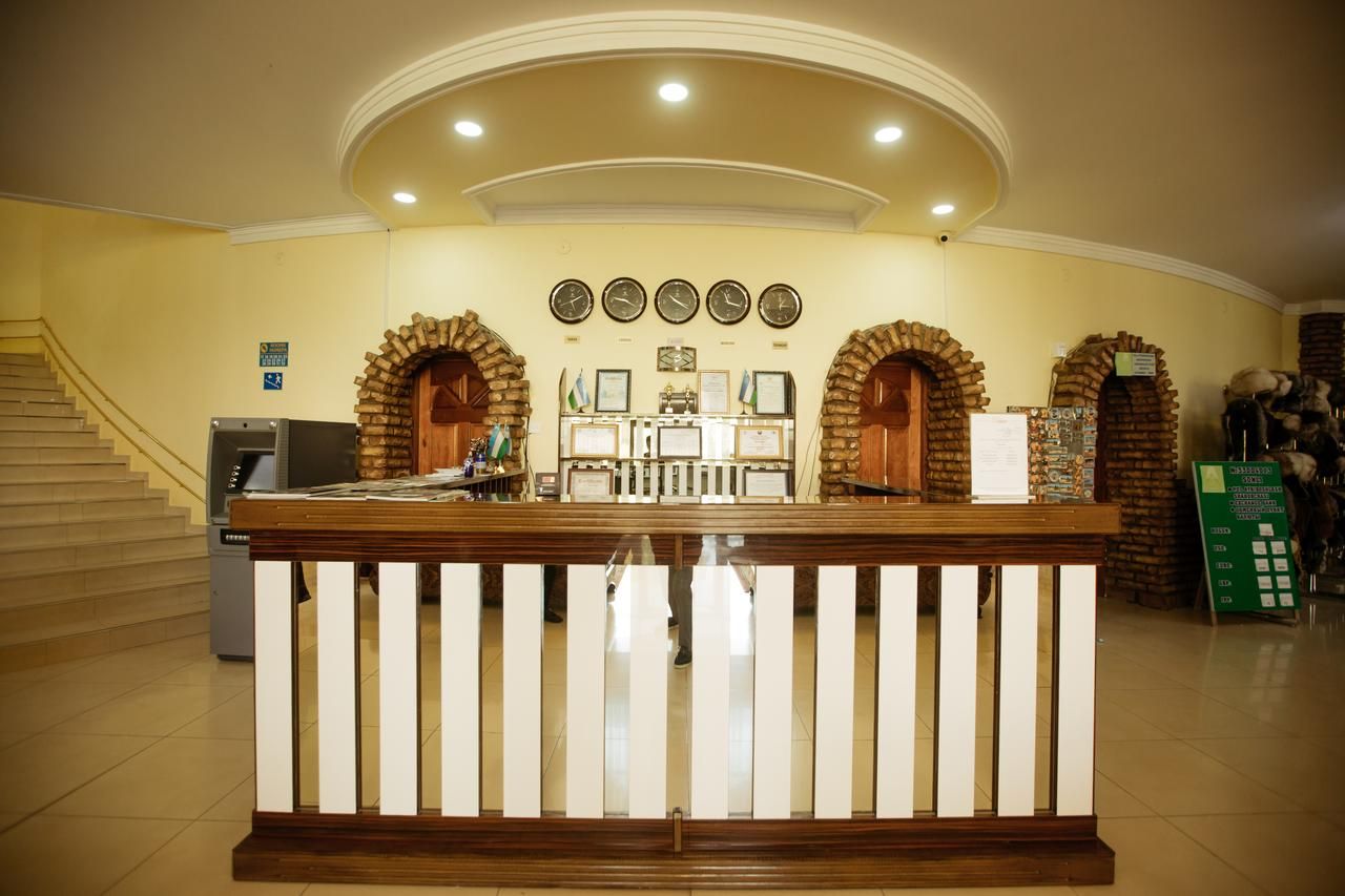 A reception area with a wooden reception desk, a staircase, and a wall with clocks and framed certificates.