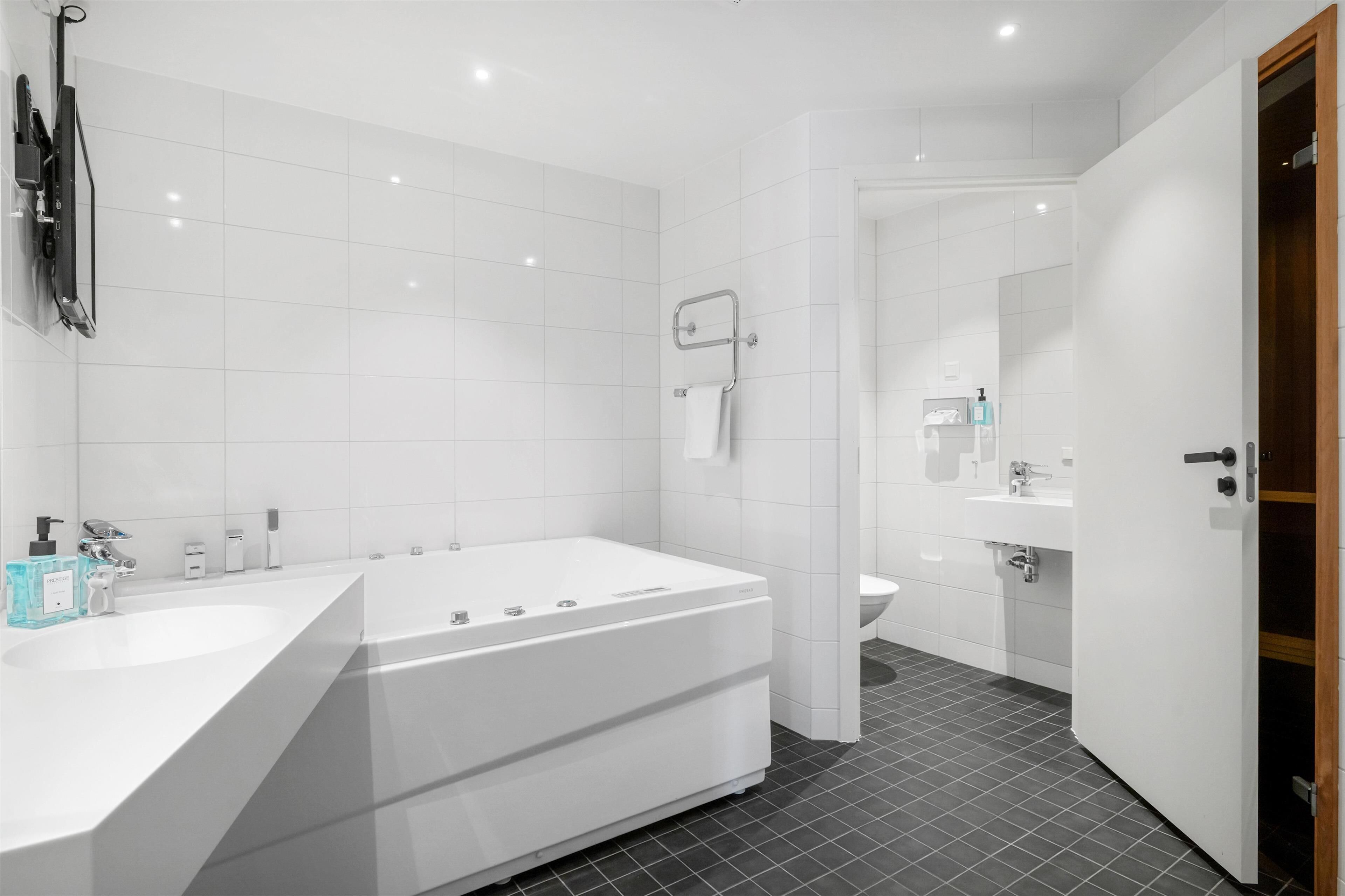 Un bagno moderno con una vasca da bagno ampia, un lavandino separato e un WC.