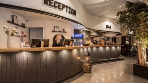 Een ontvangsthal met receptiebalie, een bar en een potplant.