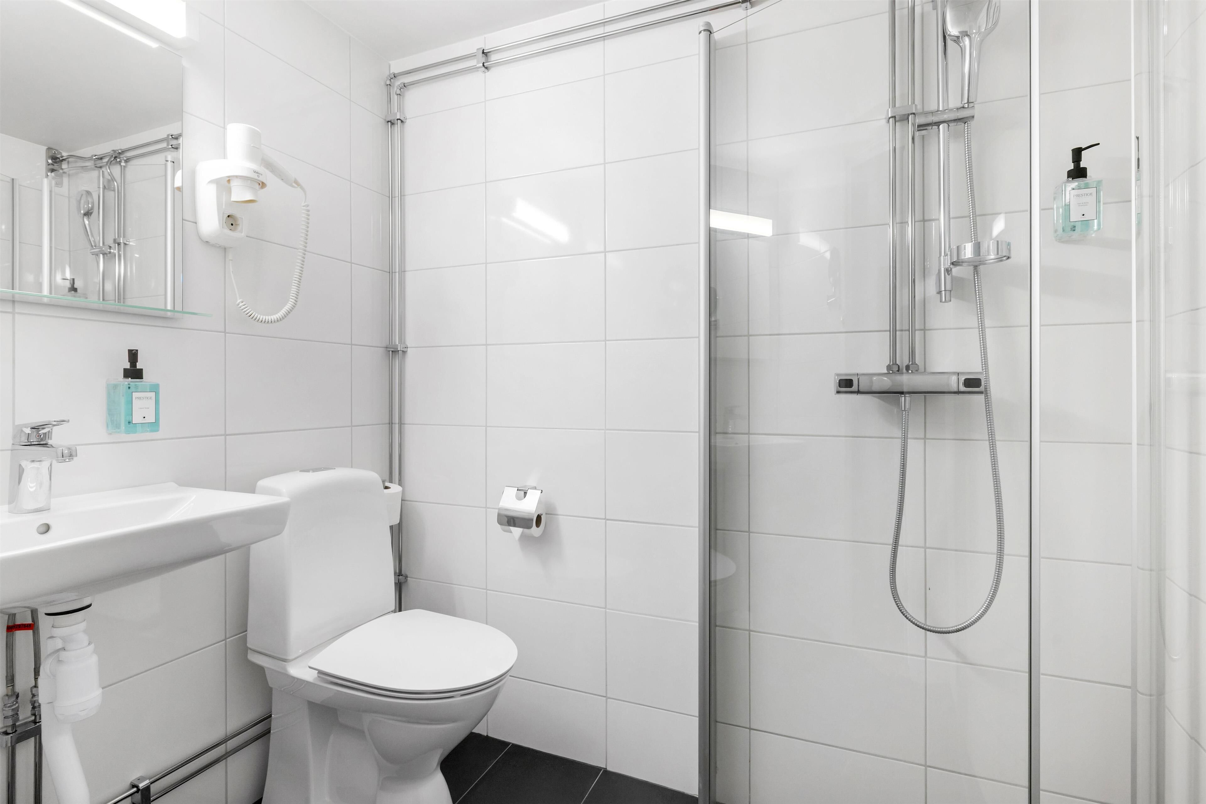 Un baño moderno con inodoro, lavabo y ducha con mampara de vidrio.