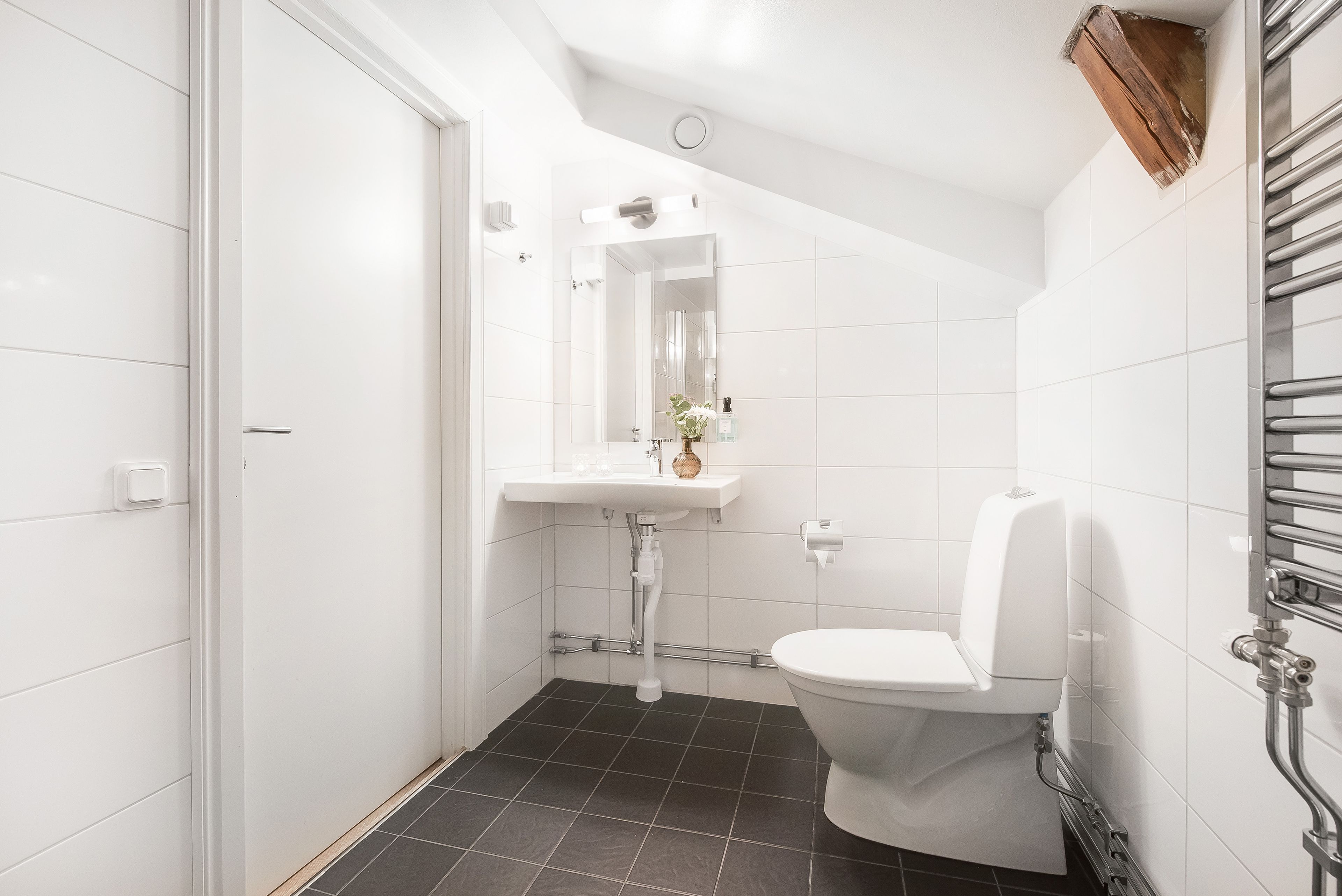 A bathroom with a white toilet, a sink with a mirror, and a shower area.