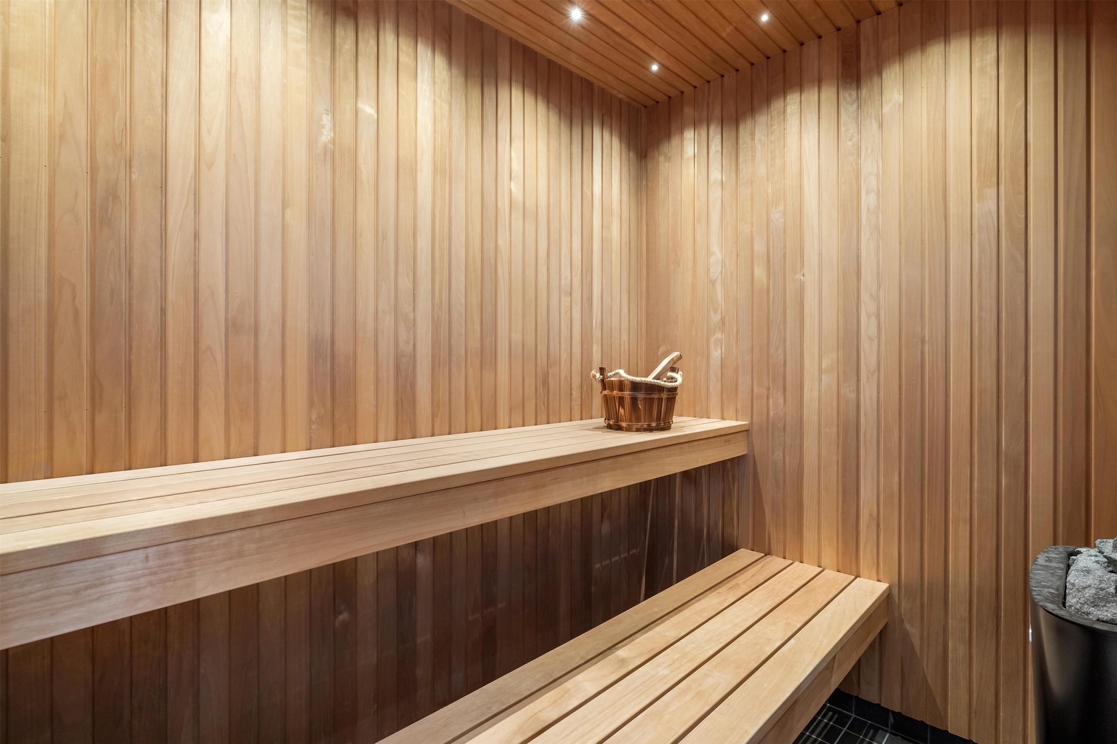 A wooden sauna with benches and a basket on a shelf.