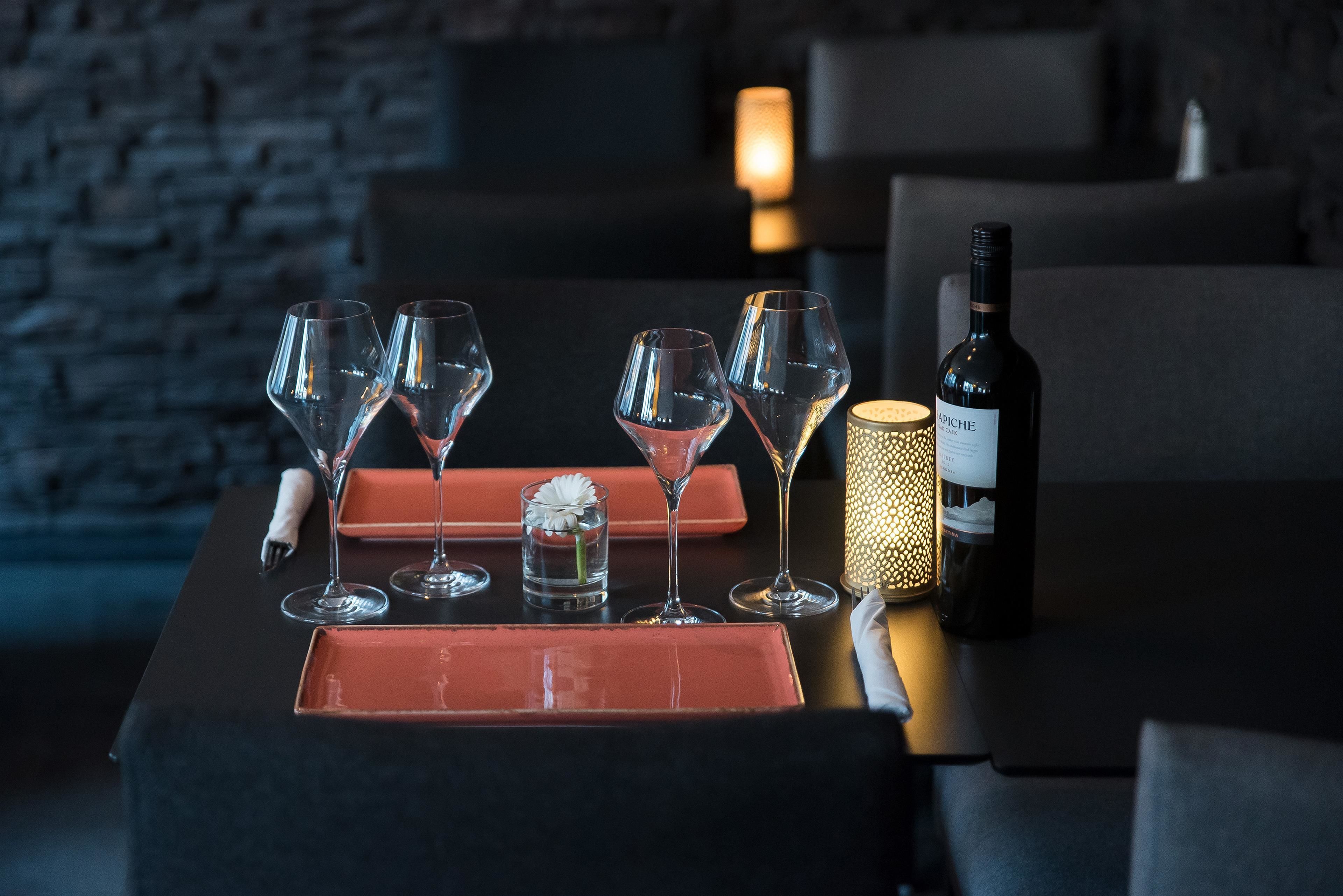 A table set with wine glasses, a bottle, and a candle.