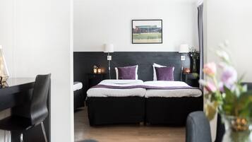 A modern hotel room with a bed, bedside tables, a lamp, and a framed picture on the wall.