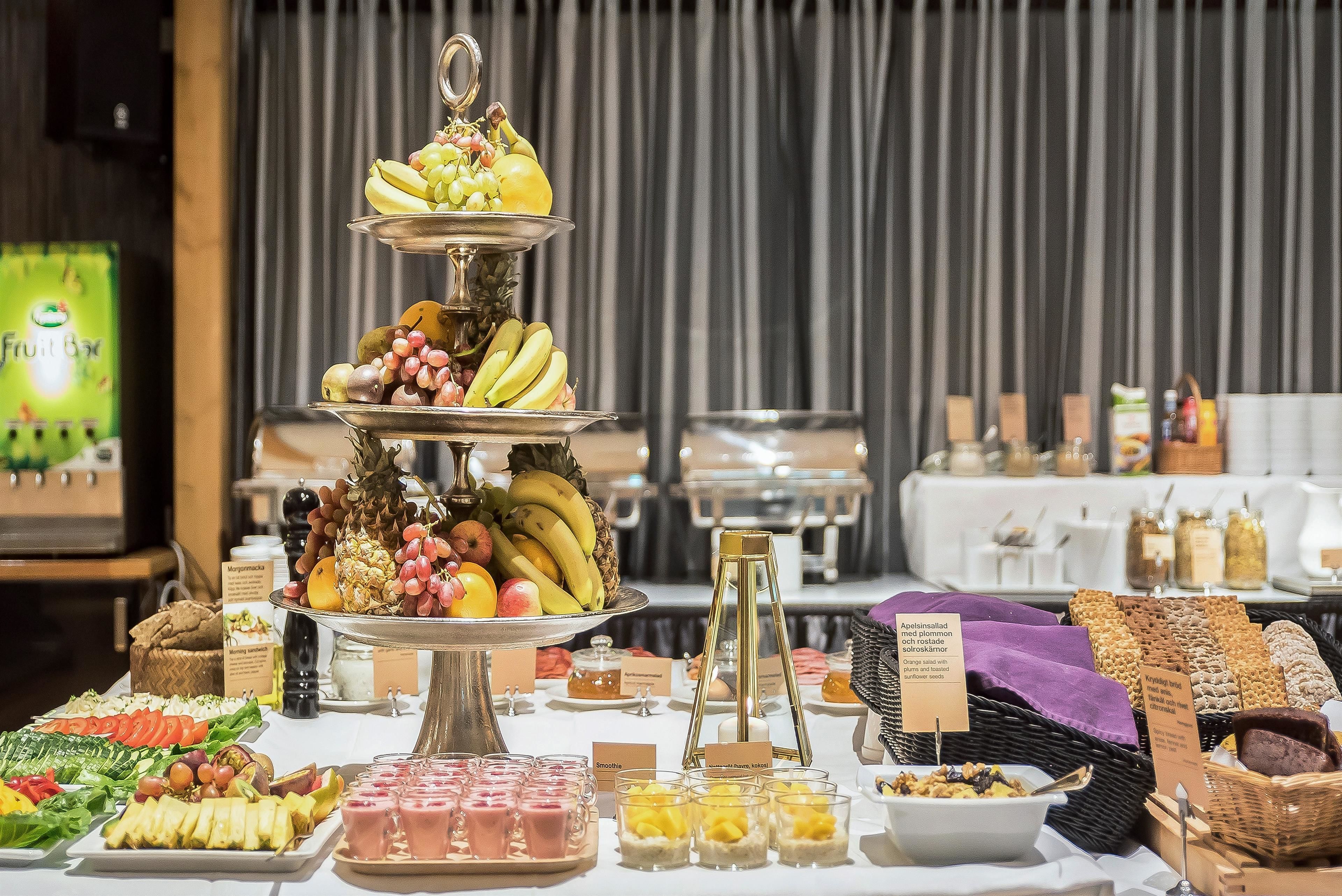 A buffet with various food items including fruits, pastries, and beverages.