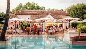 Un restaurante junto a la piscina con terraza y vistas al agua.