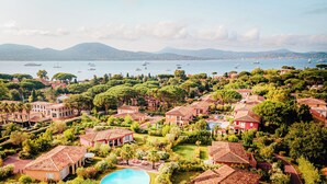 Zona residencial costera con villas, una piscina y embarcaciones al fondo.