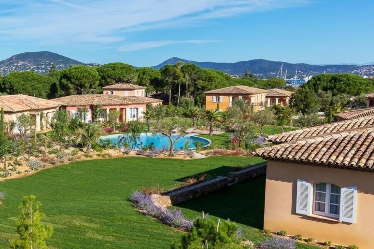 Zona residencial amb diverses cases, una piscina i un jardí ben cuidat.