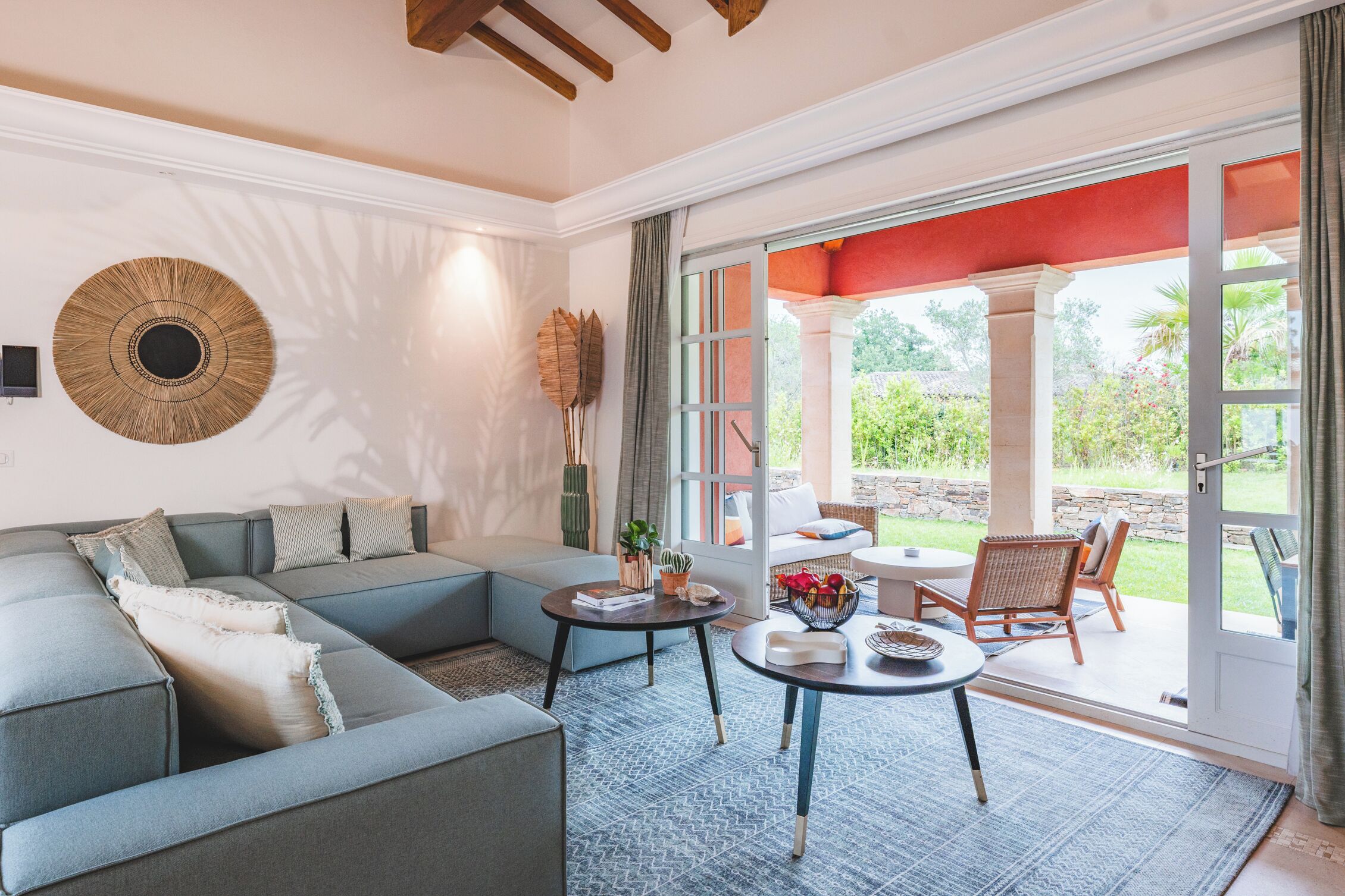 Un salon moderne avec un canapé d’angle, une table basse et un coin repas doté de chaises en osier.