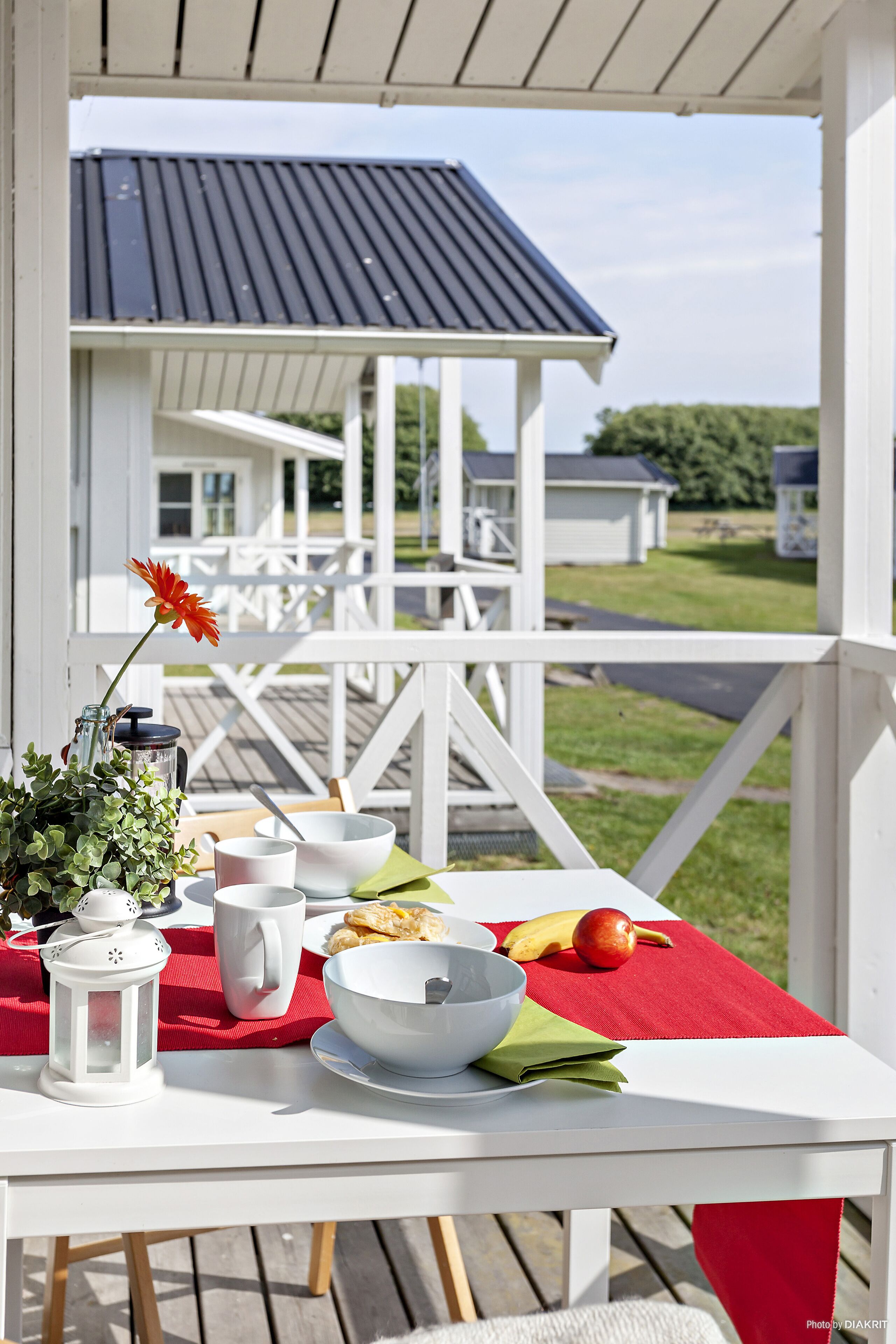 Un espacio de comedor al aire libre cubierto con una mesa dispuesta para una comida, que incluye un tazón, una taza y fruta.