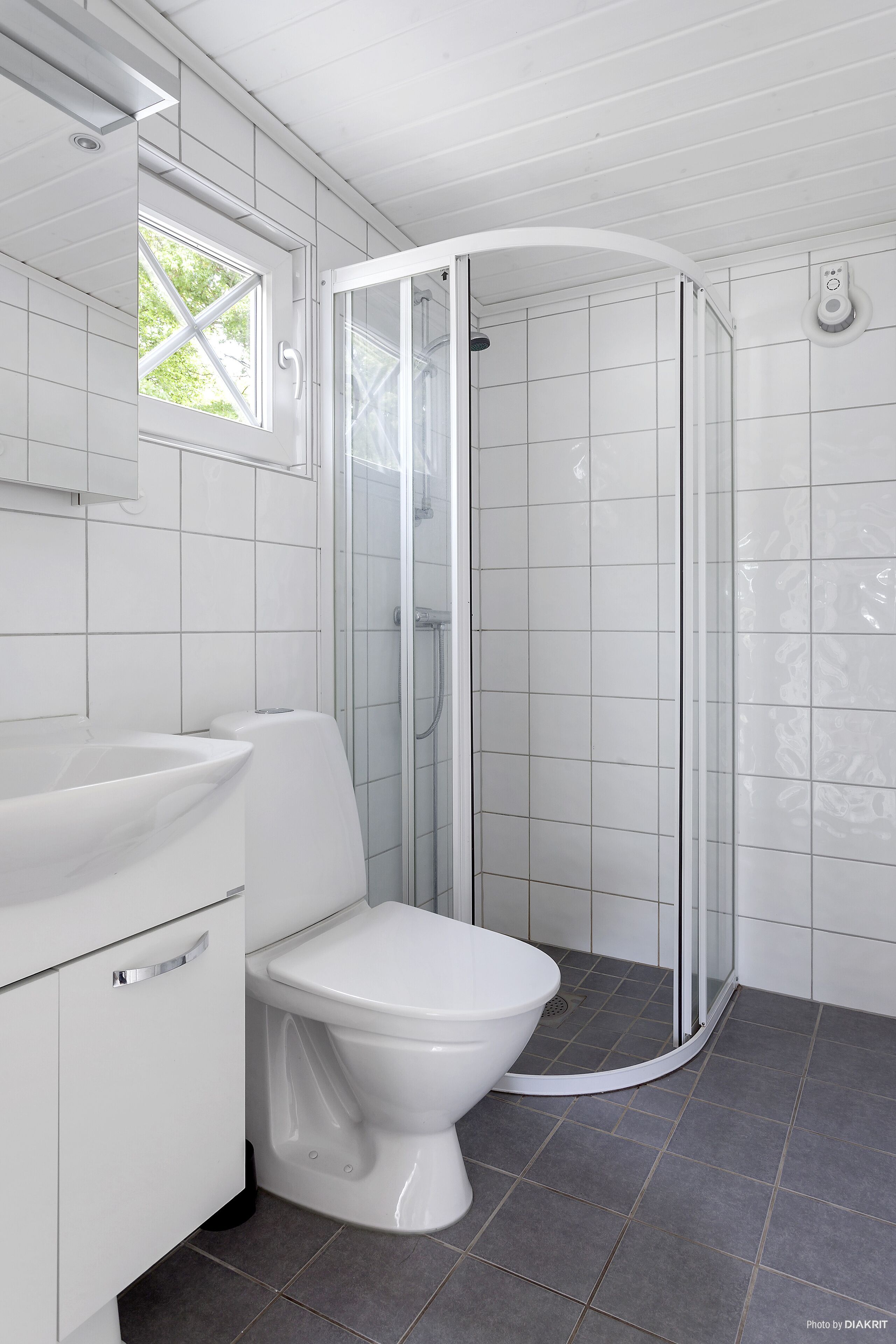 A modern bathroom with a white toilet, a sink, and a glass-enclosed shower.