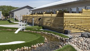 A building with a covered outdoor area, a small pond, and a wooden fence. - First Camp Malmö (Malmö)