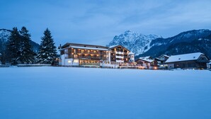 A large, multi-story hotel with a snow-covered landscape and mountains in the background. - Mareo Dolomites Hotel (Marebbe)