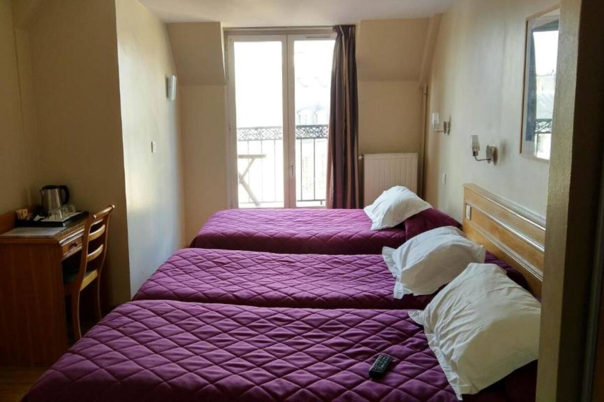 Et hotelværelse med to senge, et skrivebord og et vindue med udsigt.