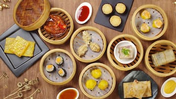 A variety of Asian dishes, including dim sum, arranged on a wooden table.