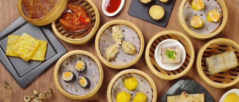 Variedad de platos asiáticos, como dim sum, dispuestos sobre una mesa de madera.