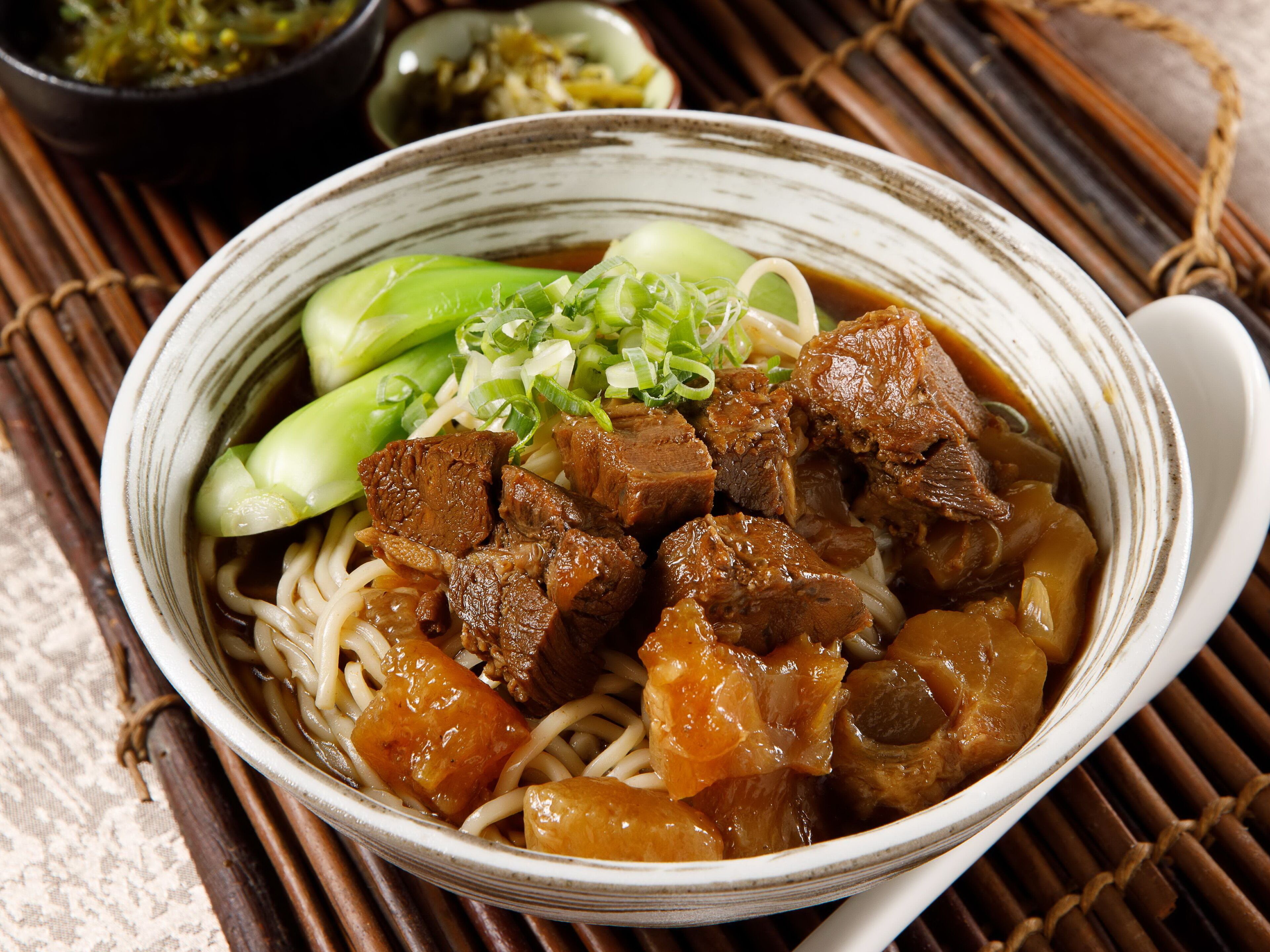A bowl of ramen with beef, vegetables, and noodles.