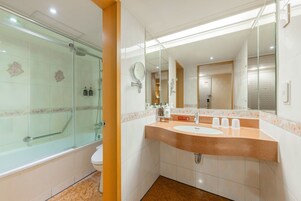 Een moderne badkamer met een douchecabine van glas, een wastafel met meerdere kraan en een grote spiegel boven het aanrecht.