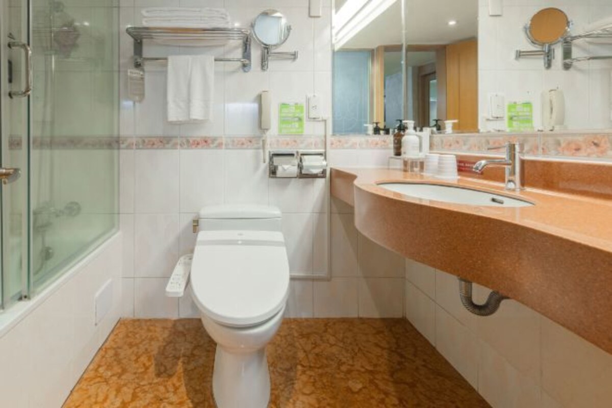 A modern bathroom with a glass shower enclosure, a white toilet, a sink with a beige countertop, and a mirror above the sink.