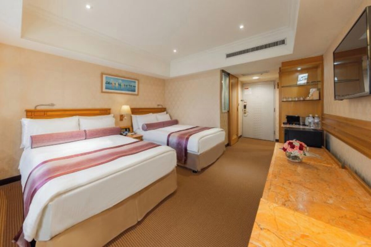 A hotel room with two beds, a marble-topped desk, a TV, and a painting on the wall.
