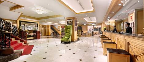 A spacious lobby with a grand staircase, a reception area, and a bar.