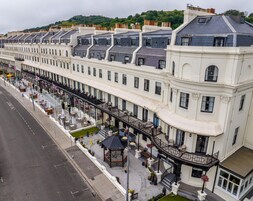 Una hilera de edificios blancos con balcones, una calle al frente y un pabellón.