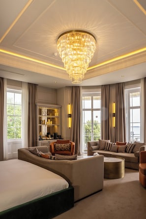 A spacious bedroom with a large bed, a sofa, a coffee table, and a chandelier. - Dover Marina Hotel & Spa, Tapestry Collection by Hilton (Dover)