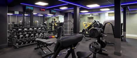 Un gimnasio con diverso equipo de ejercicio, incluyendo mancuernas, bancos y máquinas de pesas.