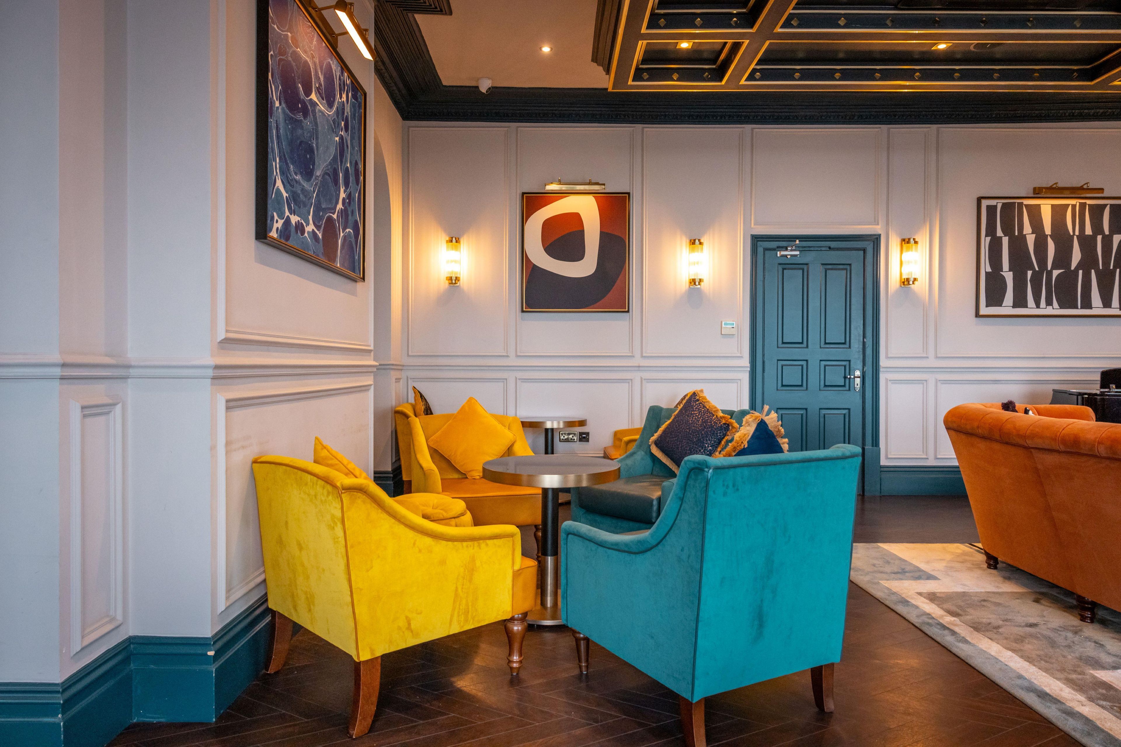 A room with a round table, two armchairs, a sofa, and a door.