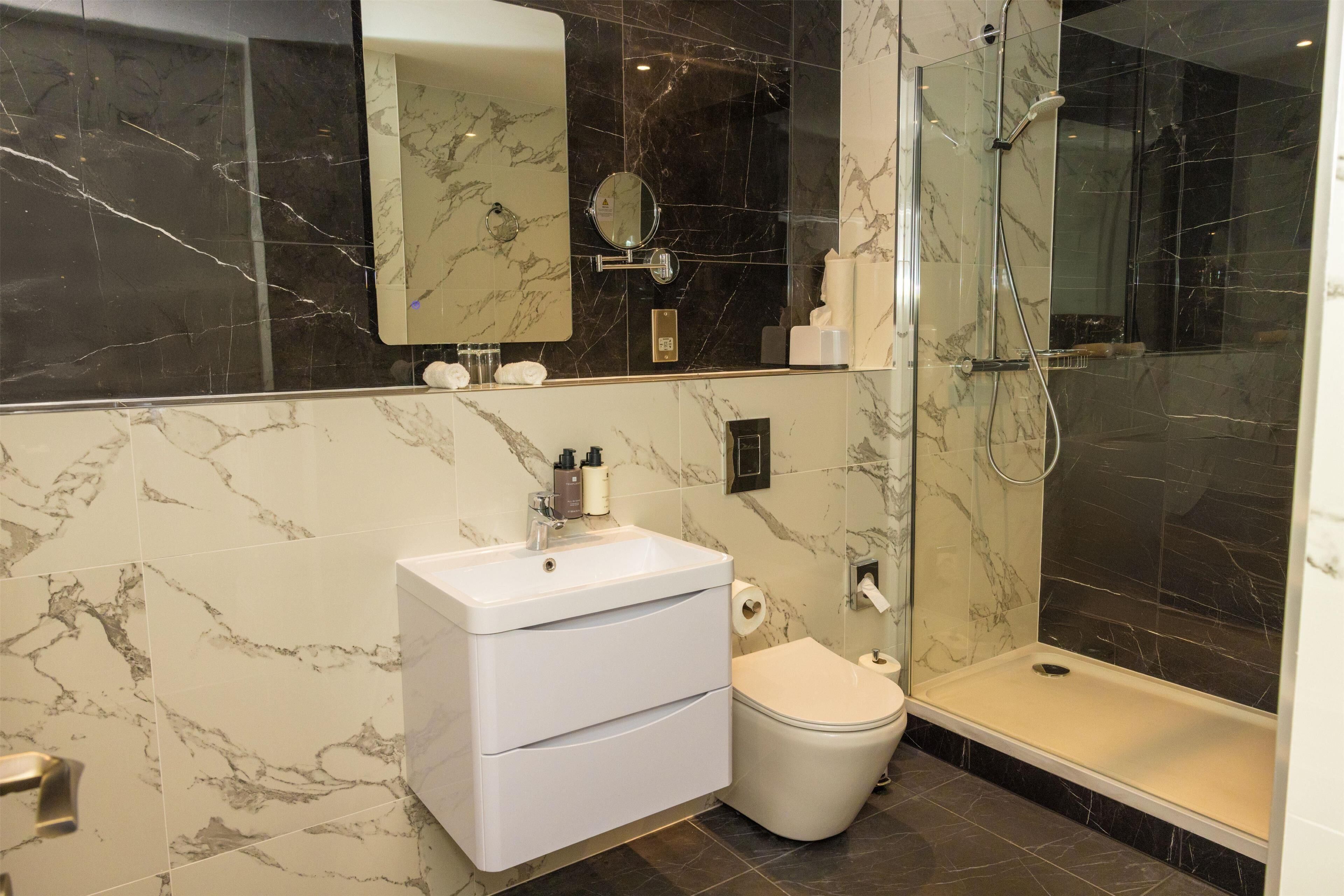 A bathroom with a marble sink, toilet, and a glass-enclosed shower.