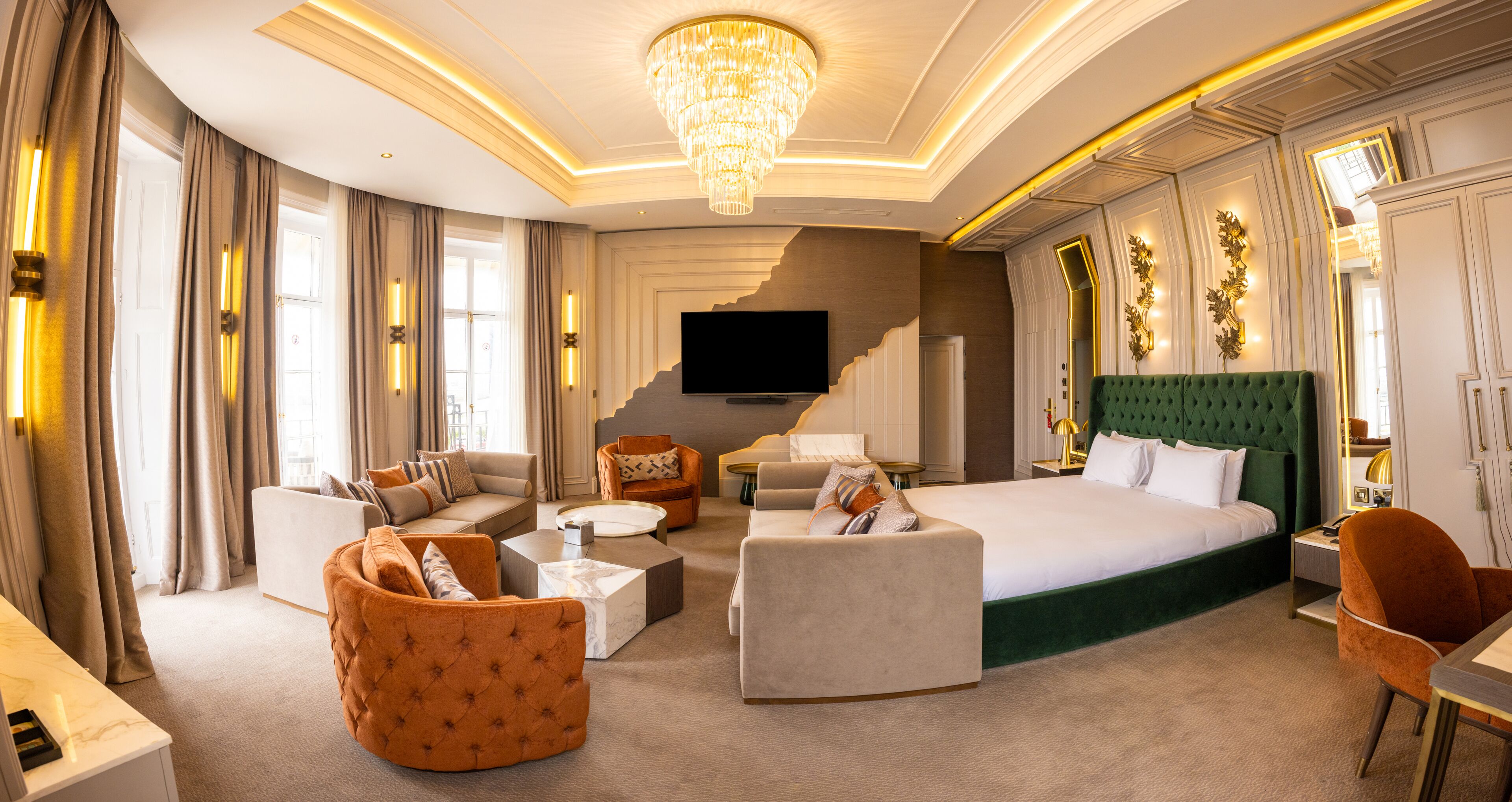 A spacious hotel room with a large bed, two sofas, a coffee table, and a television.