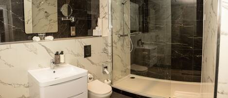 A modern bathroom with a white sink, toilet, and a glass-enclosed shower area.