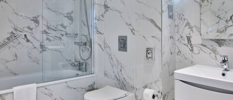 A modern bathroom with a glass-enclosed shower, a white toilet, and a vanity with a mirror.