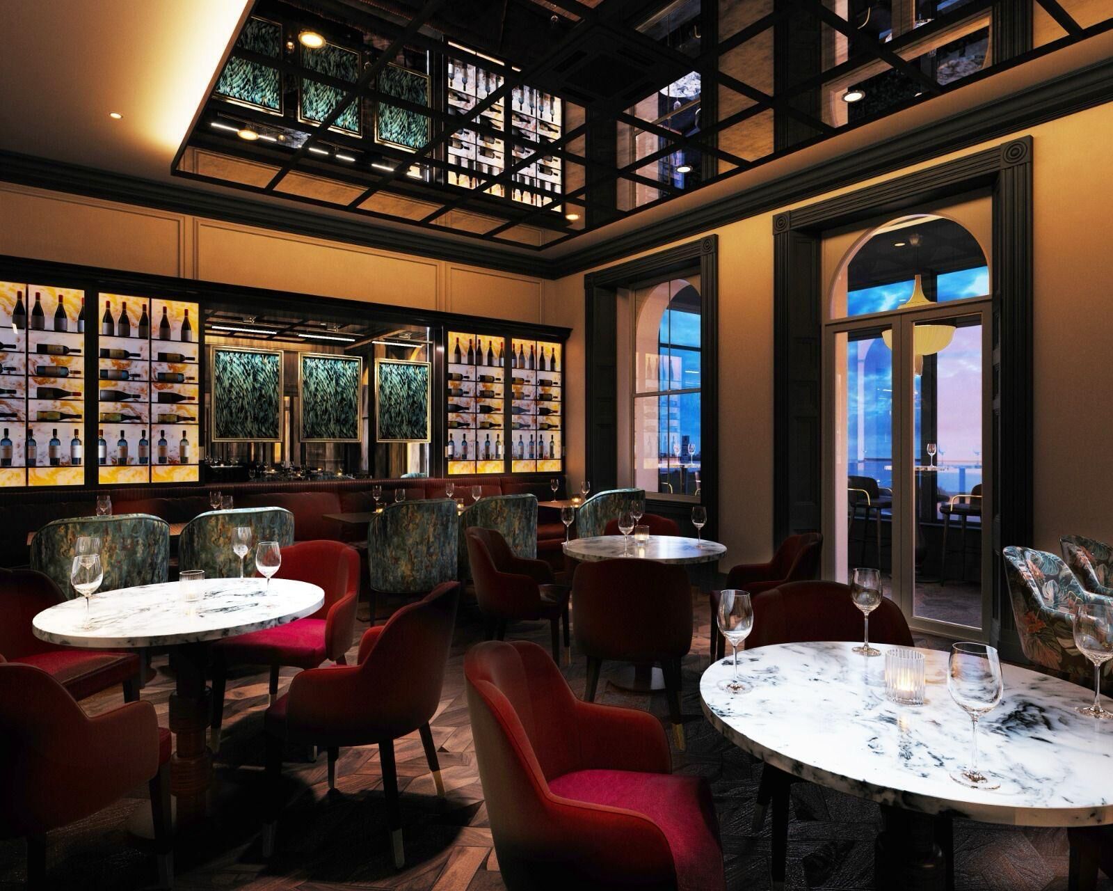 A restaurant with round tables and red chairs, a wine display, and a view through a large window.