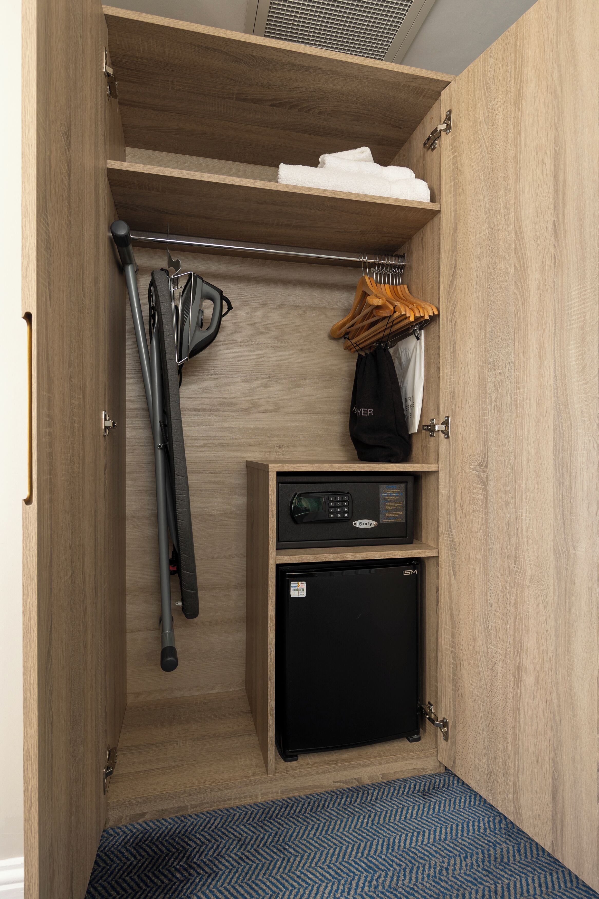 Un espacio de almacenamiento compacto con estantes, un refrigerador pequeño y un perchero.